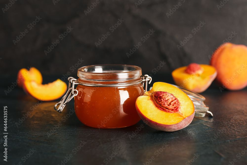 Jar with sweet peach jam on black background