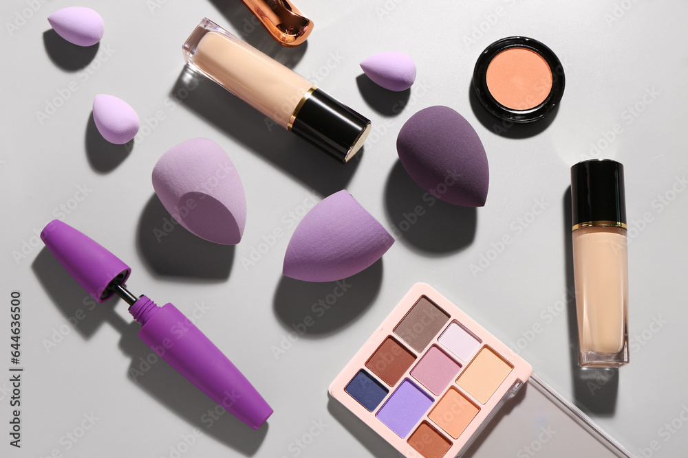 Composition with different makeup sponges and cosmetics on grey background