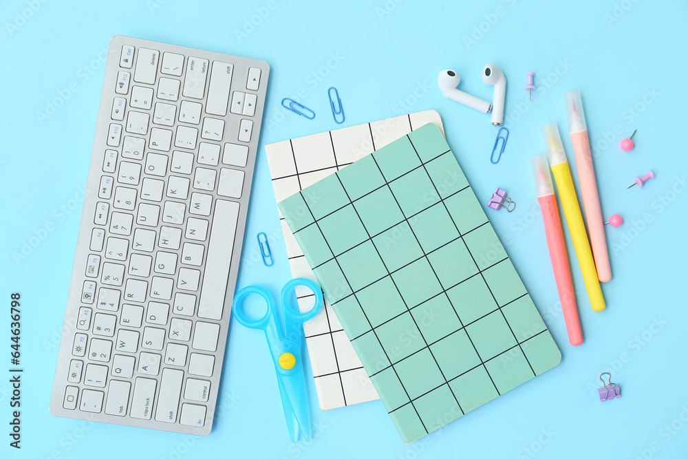 Composition with different stationery, earphones and keyboard on color background