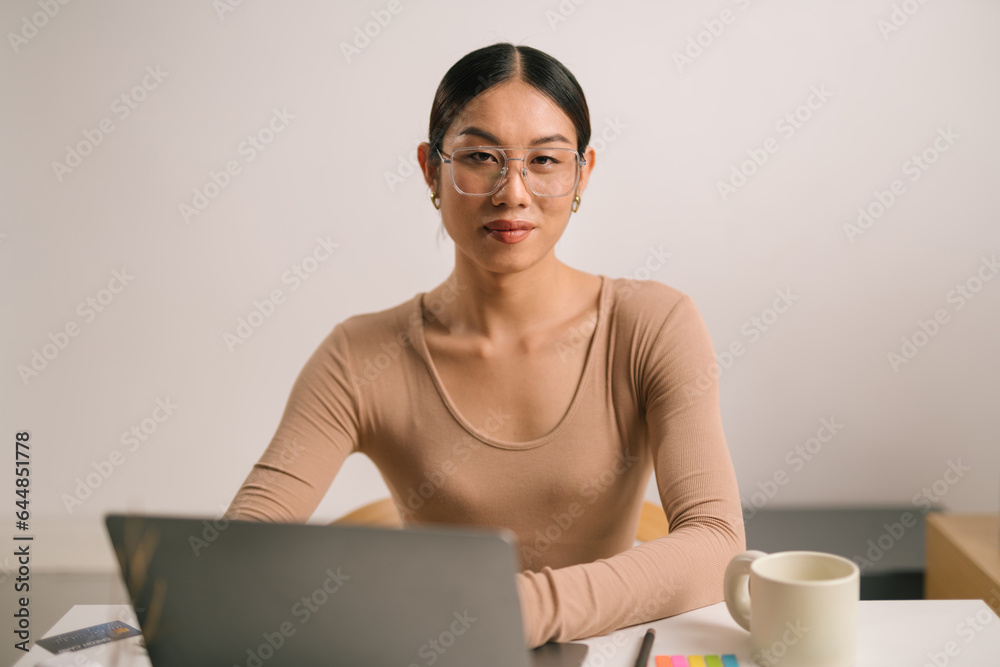 Asian male in eyeglasses using laptop computer while sitting at home office desk. LGBT