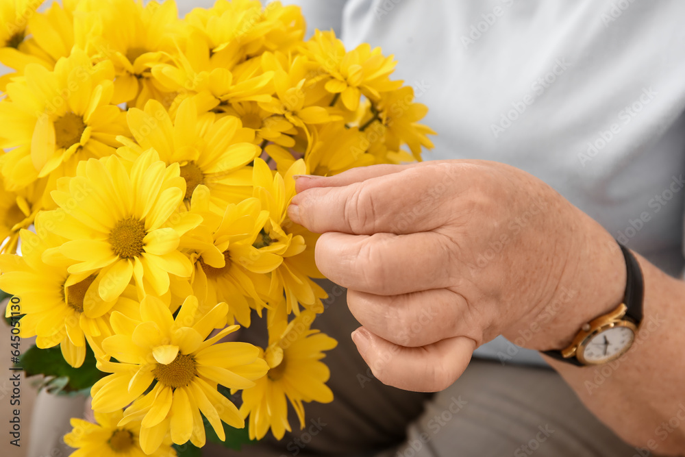 Senior woman with chrysanthemum flowers at home, closeup