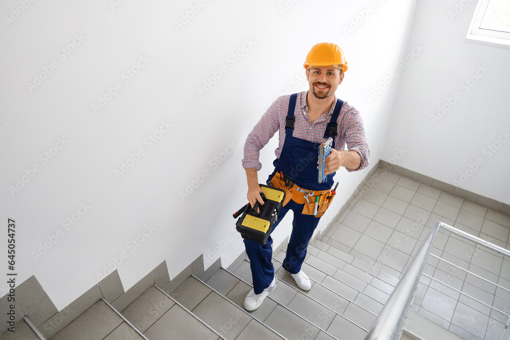 Male builder with tool bag in stairway