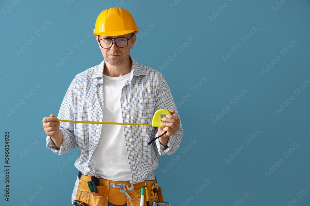 Mature builder with tape measure on blue background