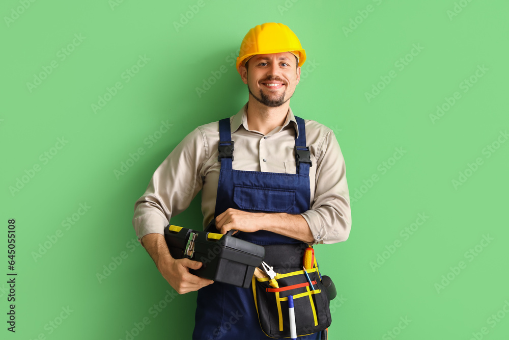 Male builder with tool bag on green background