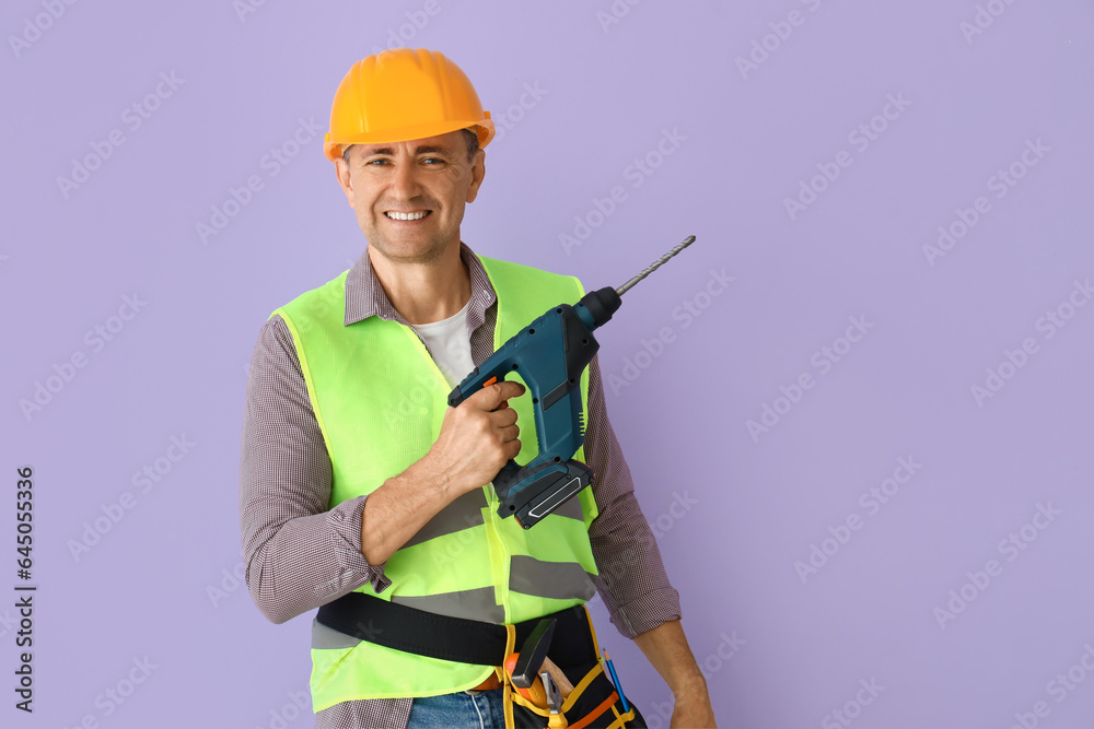 Mature builder with drill on lilac background