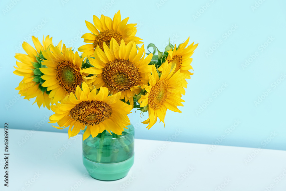 Vase with sunflowers on shelf near blue wall