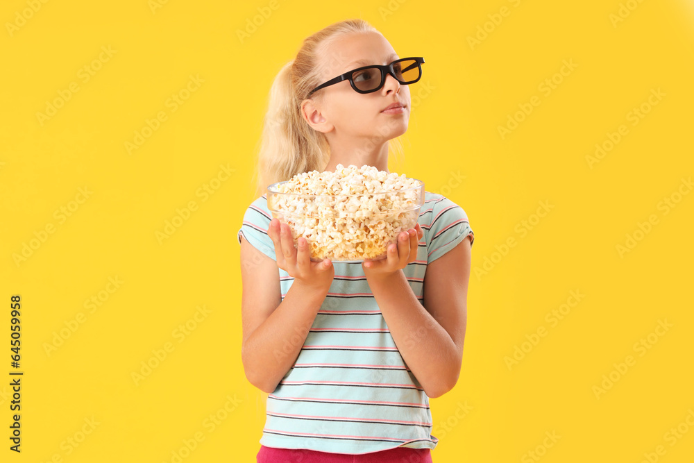 Cute girl in 3D cinema glasses with bowl of popcorn on yellow background