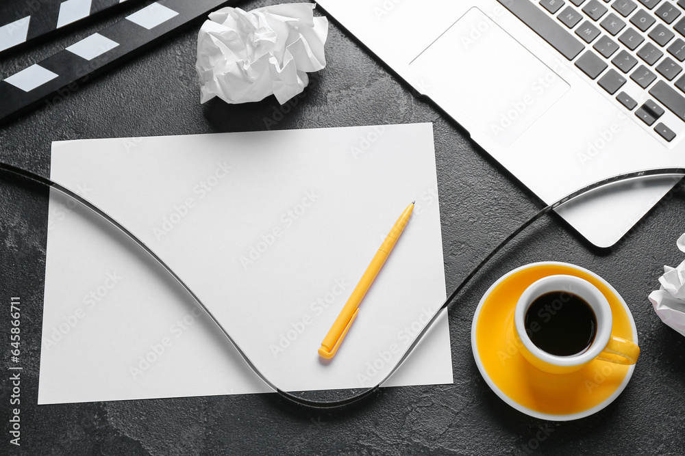 Blank paper sheet with film, cup of coffee and laptop on dark background