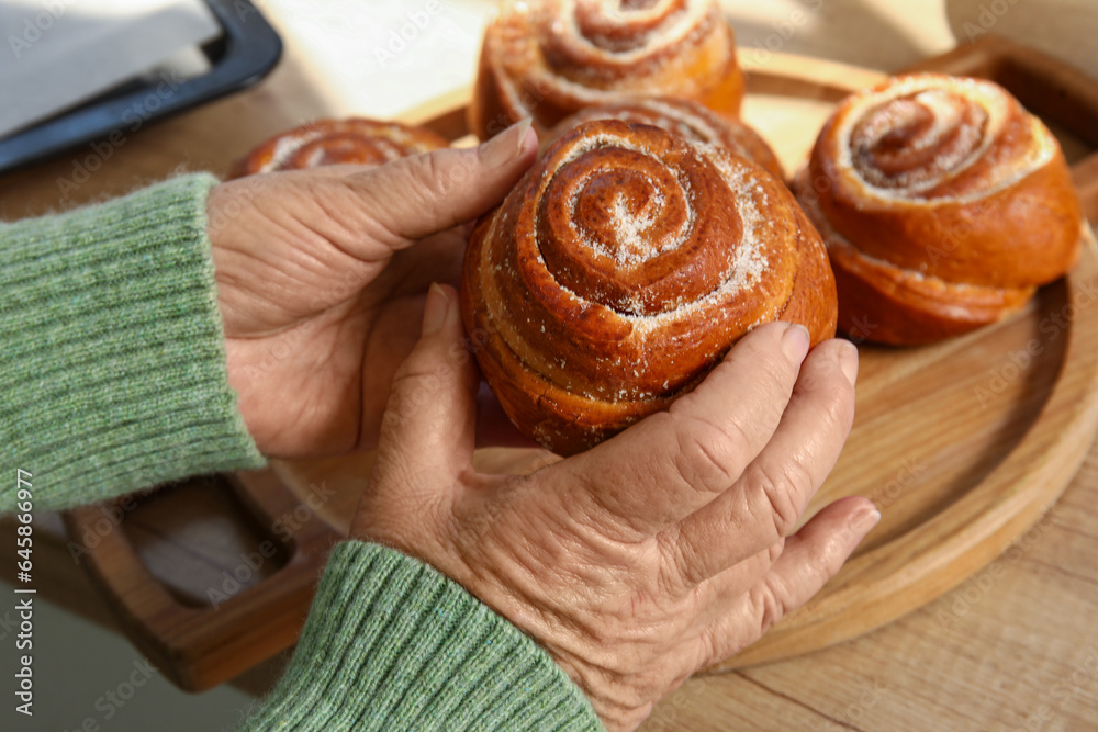 Senior woman with tasty buns in kitchen, closeup