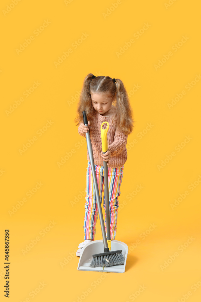 Cute little girl with broom and dustpan on yellow background