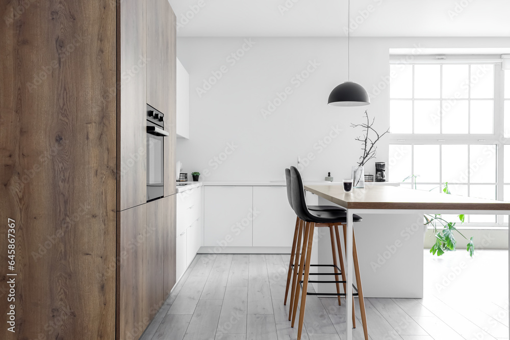 Interior of modern kitchen with island, built-in oven and white counters