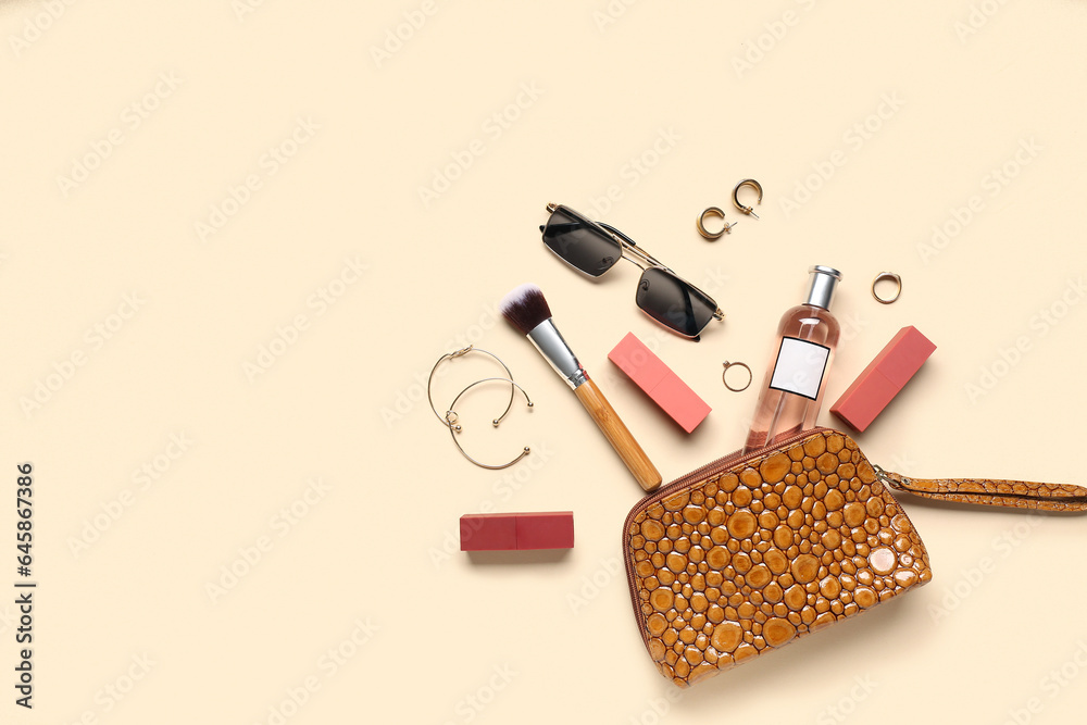 Cosmetic bag with sunglasses, makeup products and accessories on pale orange background