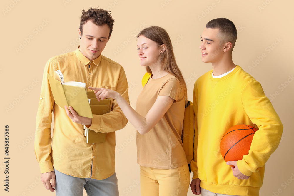 Group of students with books and ball on pale yellow background