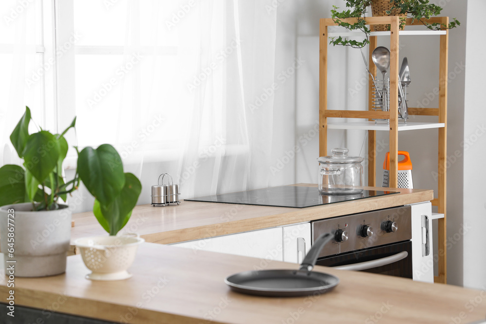 Electric stove with cooking pot on wooden countertop in interior of modern kitchen