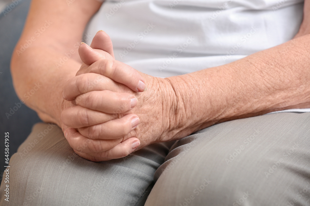 Hands of senior woman sitting at home, closeup