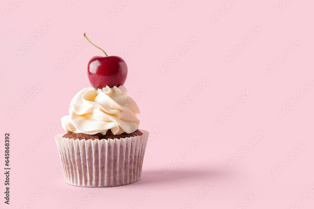 Tasty cherry cupcake on pink background