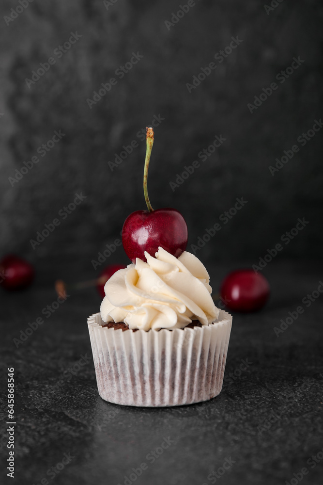 Tasty cherry cupcake on black background