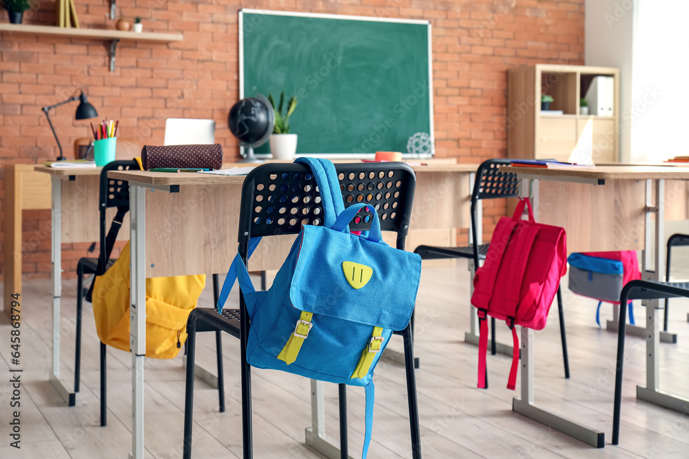 Interior of stylish empty classroom with backpacks and stationery