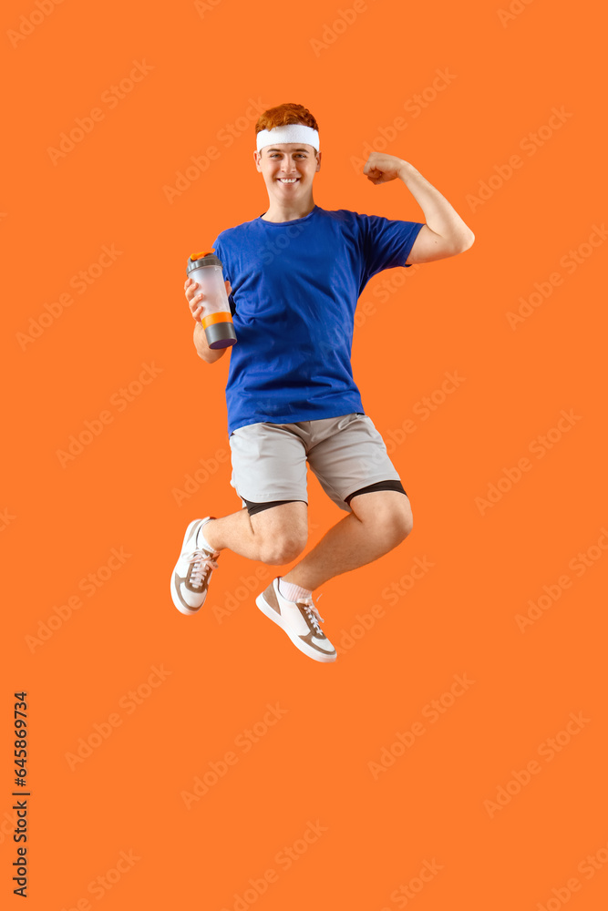 Sporty jumping young man with bottle of water on orange background