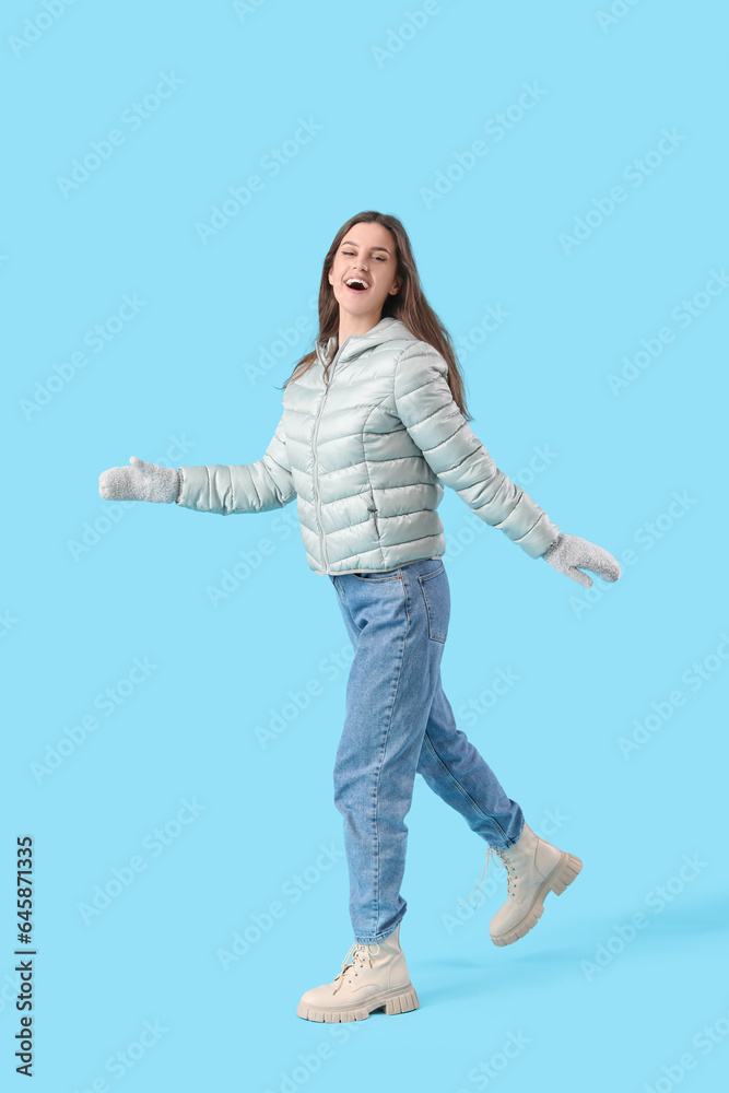 Young woman in winter clothes on blue background