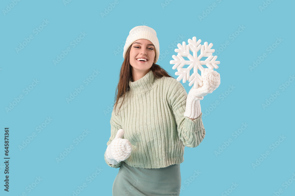 Young woman in winter clothes with snowflake on blue background