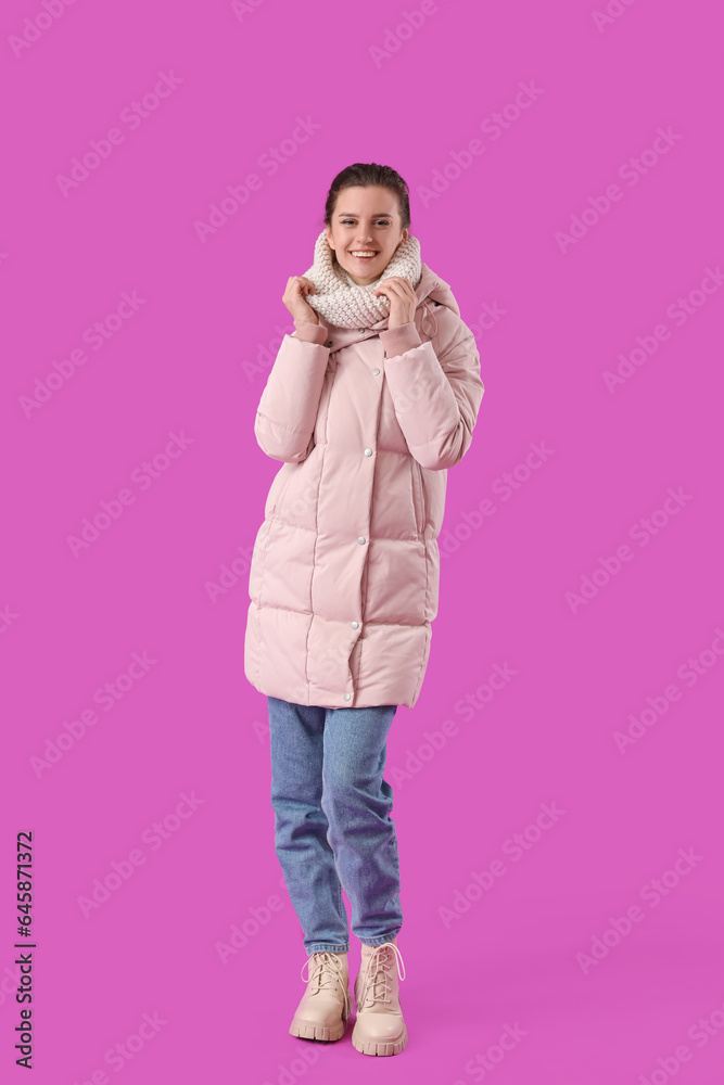 Young woman in down coat on purple background