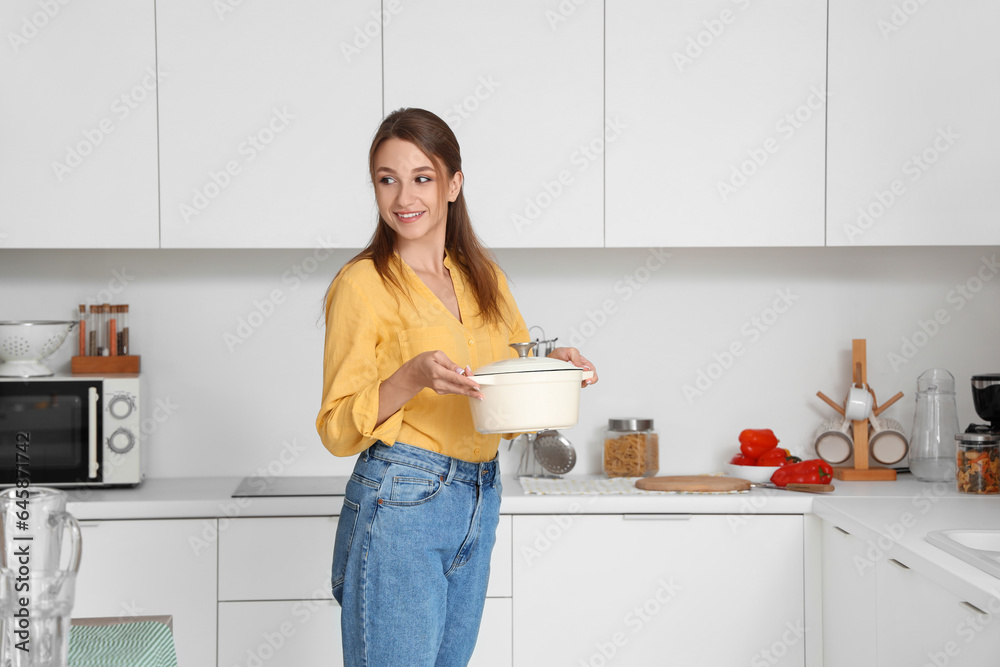 Young woman with chicken soup in kitchen