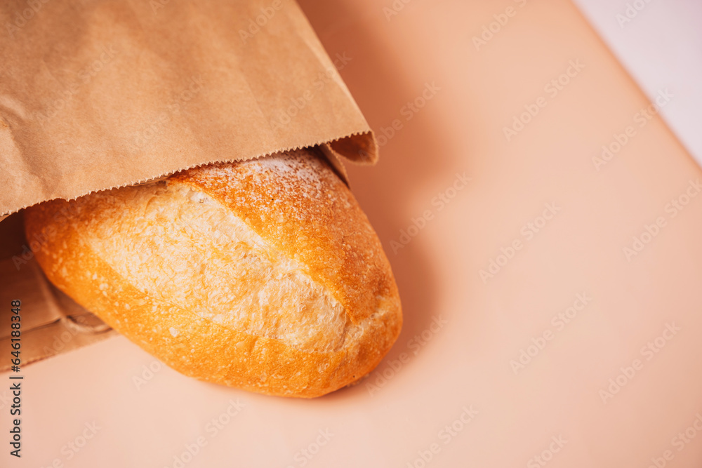 Freshly baked loaf of bread from a paper bag on the table.