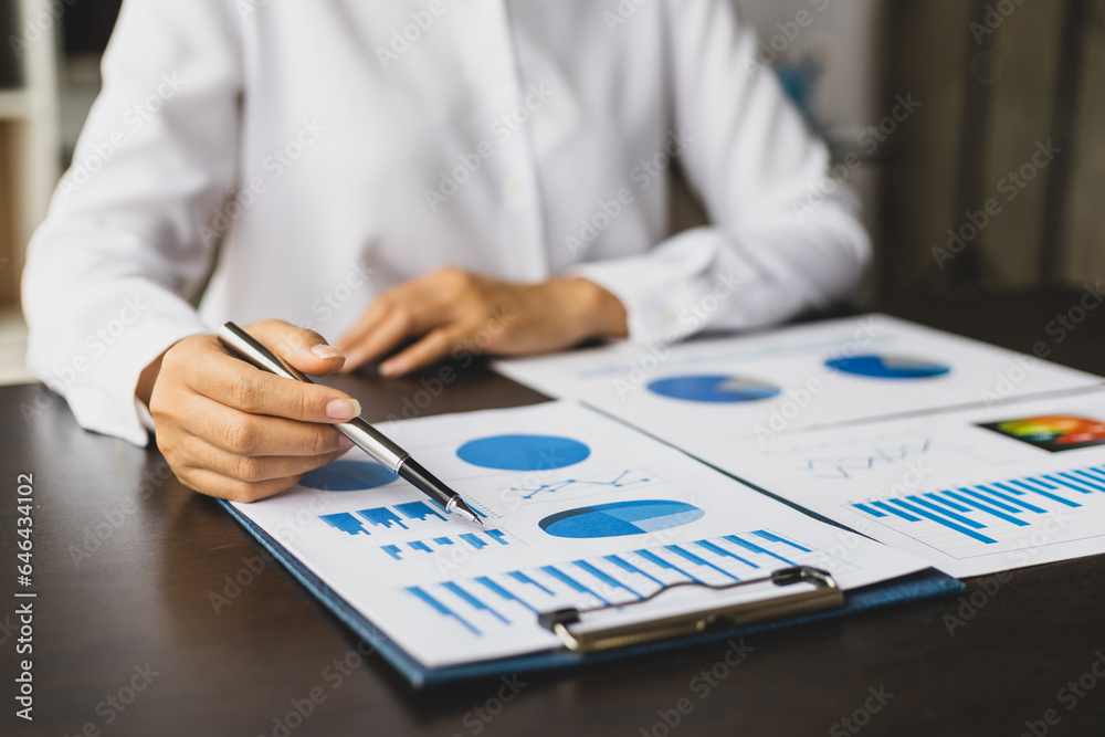 Businesswoman working on documents analyzing business finance charts and planning investments.