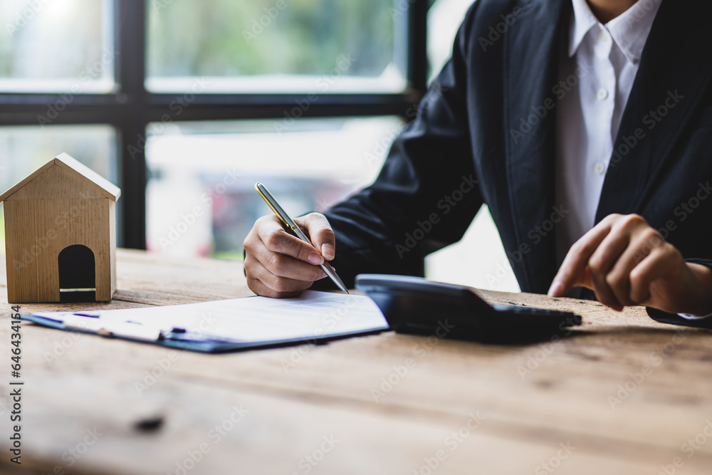 Businesswoman, real estate agent reading contract documents and calculating real estate budget.