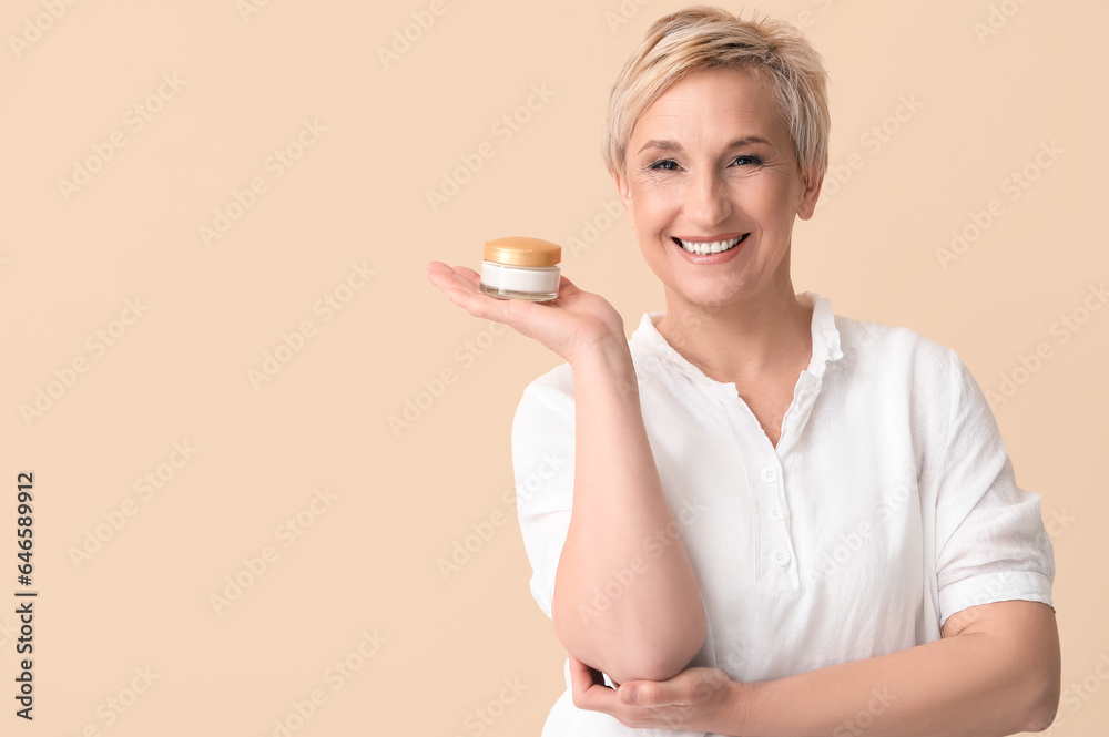 Mature woman with jar of cream on beige background