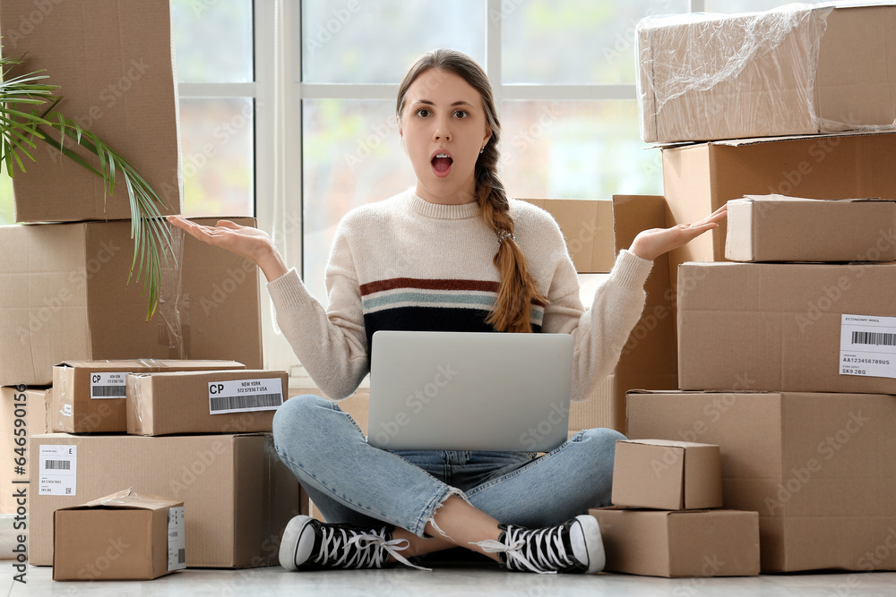 Shocked young woman with parcels and laptop at home