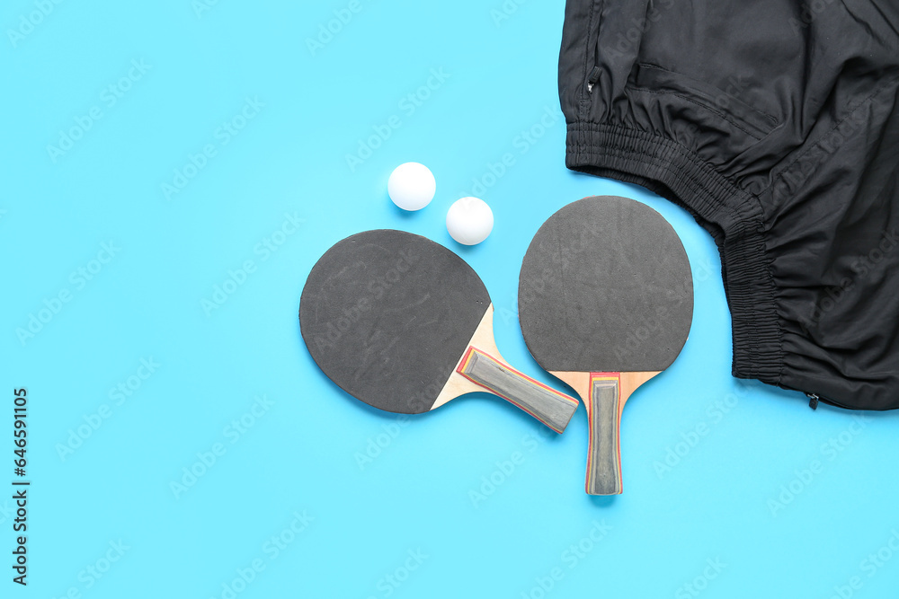 Ping pong rackets, balls and clothes on color background