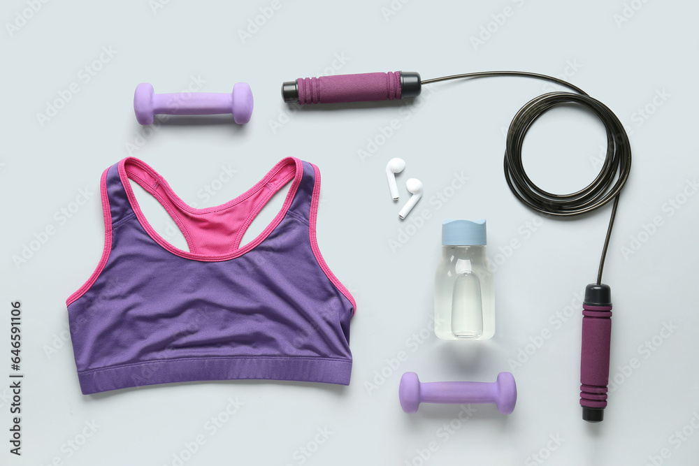 Set of sports equipment, clothes and earphones on light background