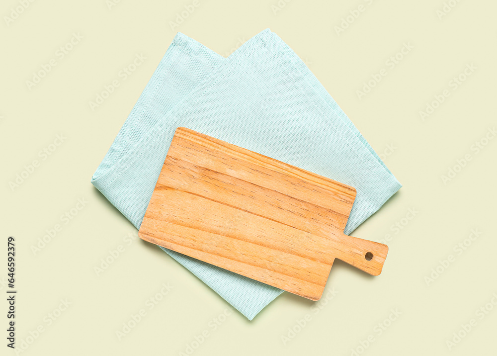 Wooden cutting board and clean napkin on color background