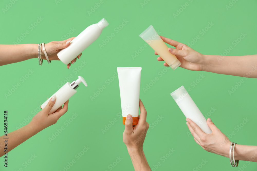 Female hands with bottles of sunscreen cream on green background