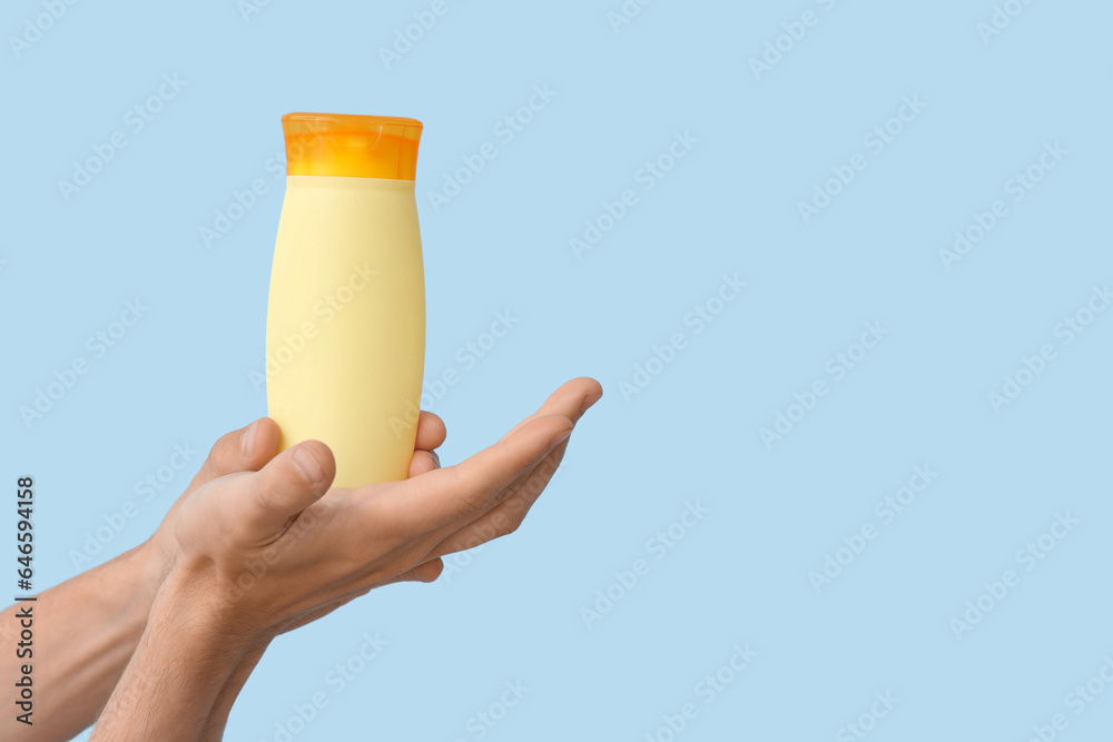 Female hands with bottle of sunscreen cream on blue background