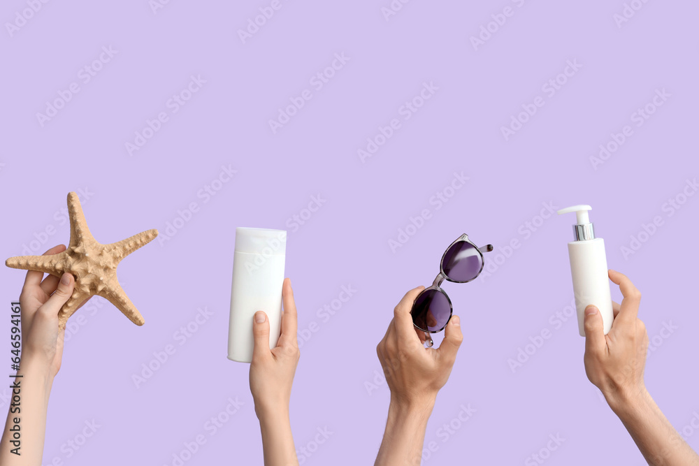 Female hands with bottles of sunscreen cream, starfish and sunglasses on lilac background