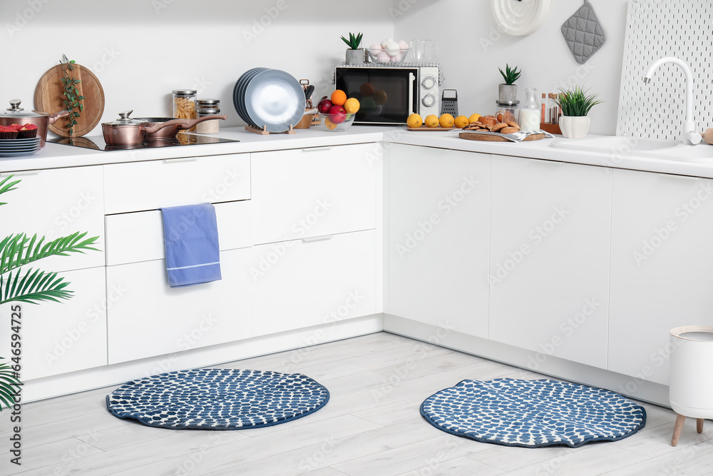 Interior of modern kitchen with stylish rugs and white counters