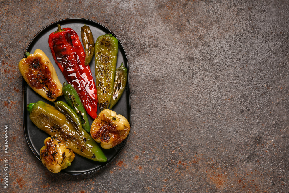 Tray with different grilled peppers on dark background