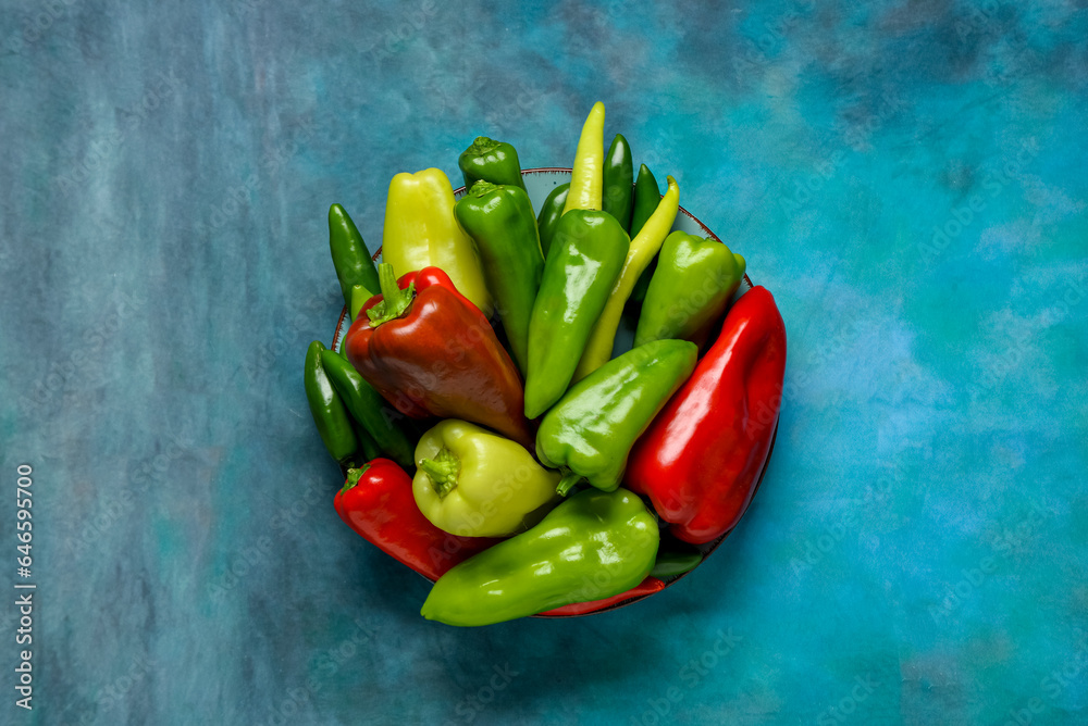 Plate with different fresh peppers on blue background