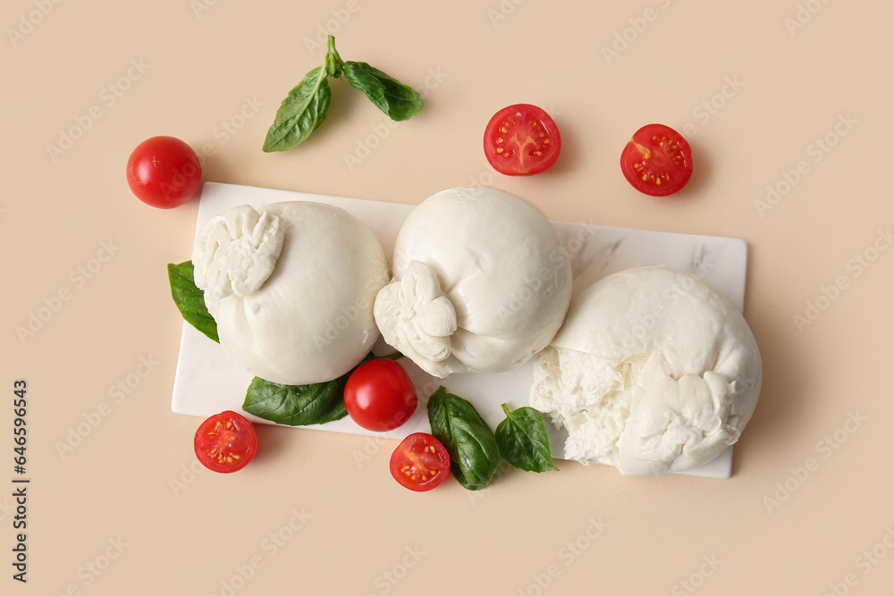 Board of tasty Burrata cheese with basil and tomatoes on beige background