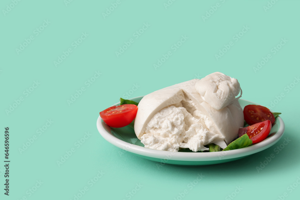 Plate of tasty Burrata cheese with basil and tomatoes on turquoise background