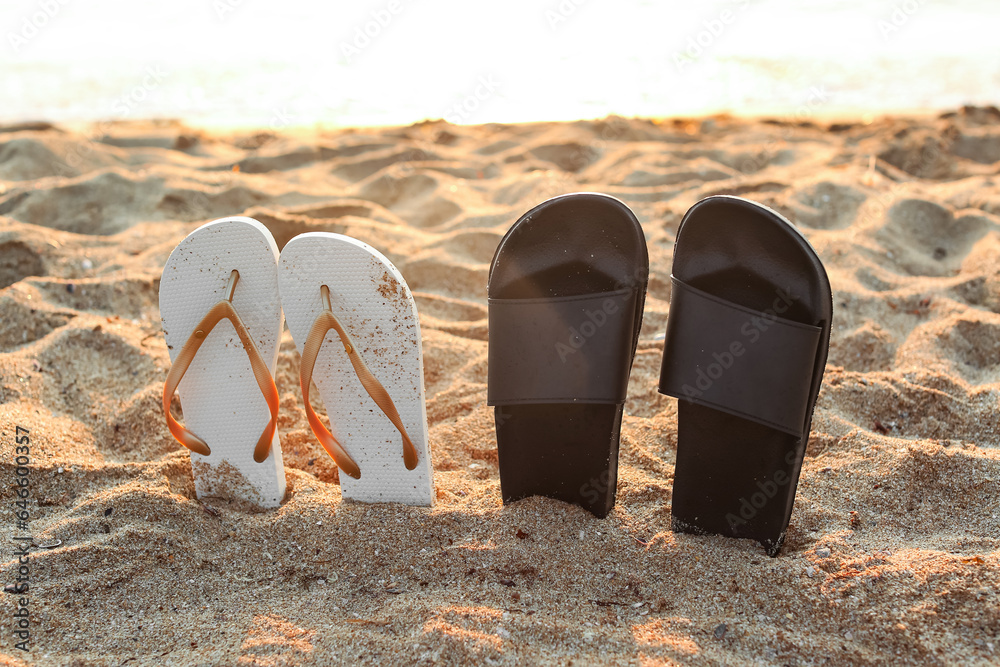 Stylish flips flops on sand near ocean at resort