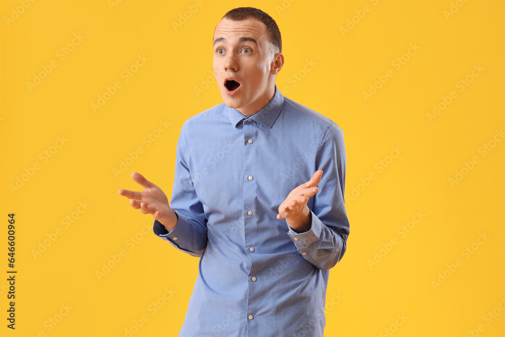 Shocked young man on yellow background