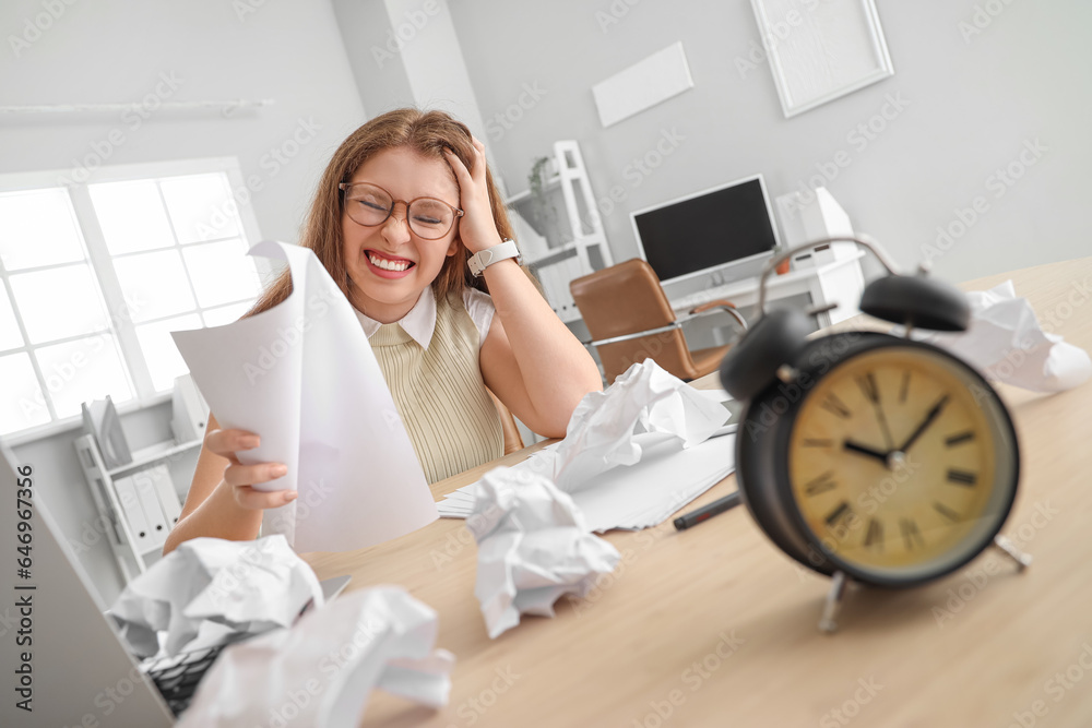 Stressed young businesswoman with papers working under deadline in office