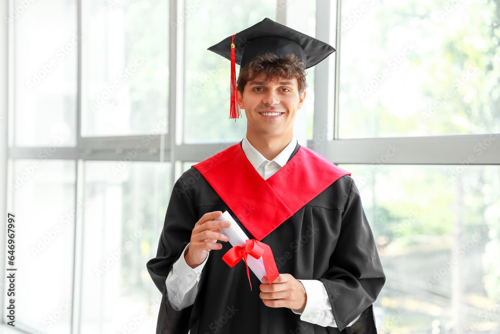 Male graduate student with diploma near window in room