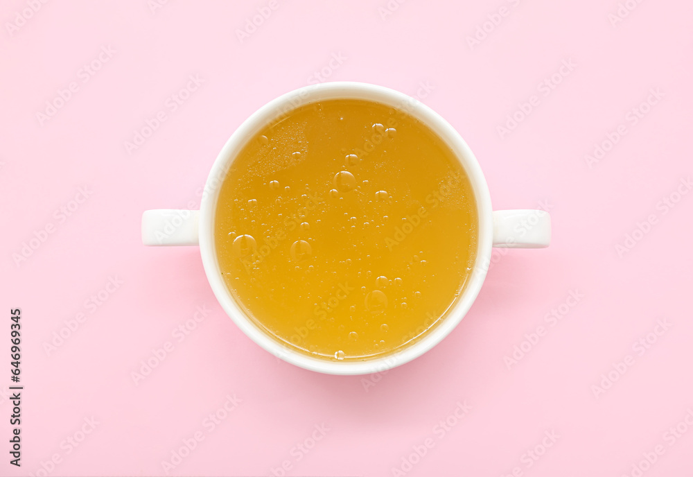 Pot of tasty vegetable broth on pink background