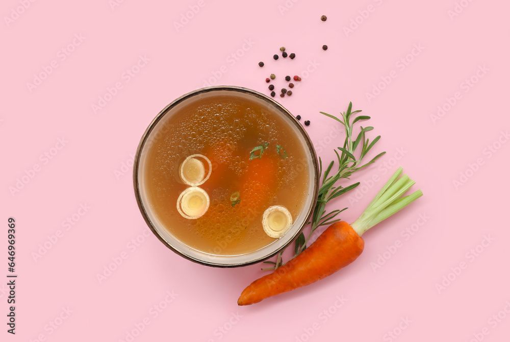 Bowl of tasty vegetable broth on pink background