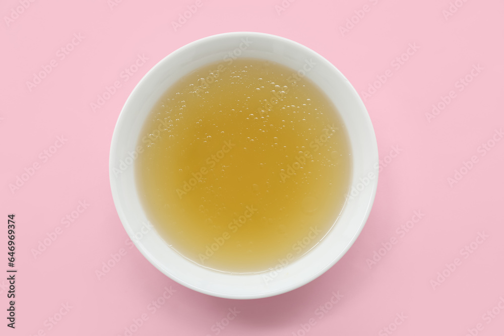 Bowl of tasty vegetable broth on pink background